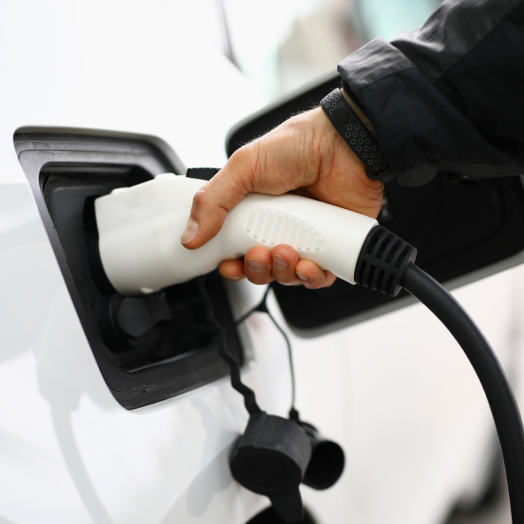 Ręka trzymająca wtyczkę do ładowania samochodu elektrycznego