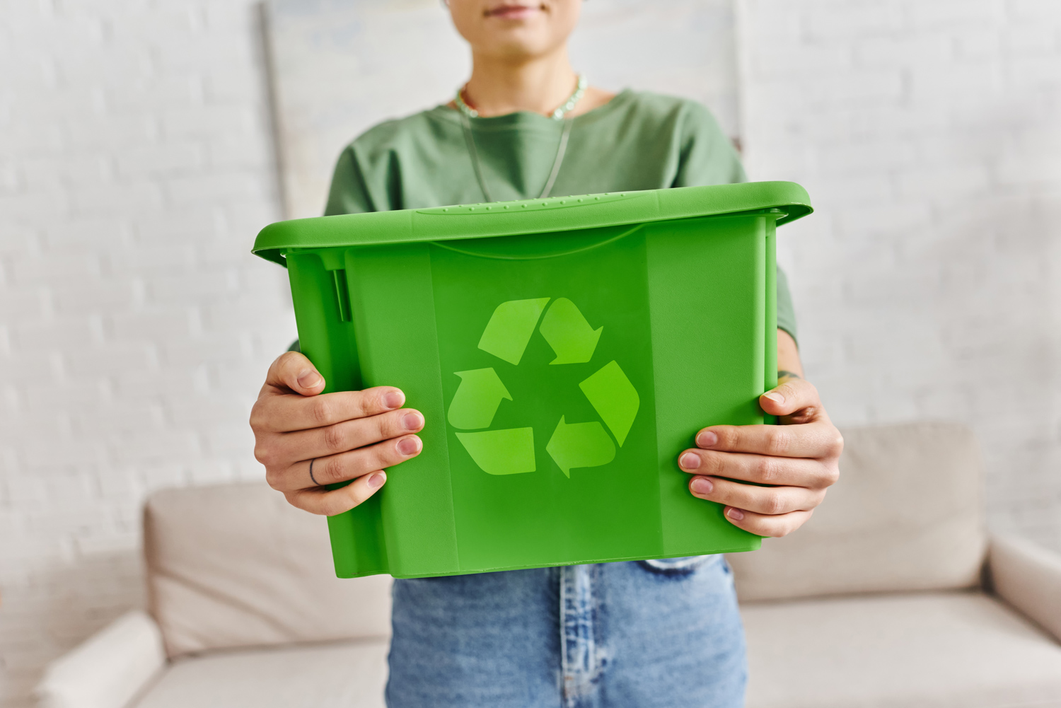 Osoba trzymająca zielony pojemnik z symbolem recyklingu – informacja o zbiórce odpadów w M1 Radom