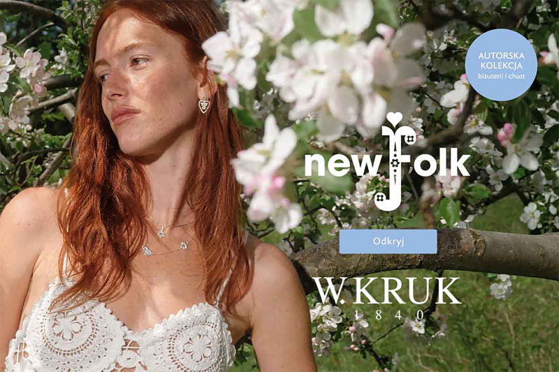 Grafika promocyjna marki W.KRUK. Rudowłosa kobieta reklamująca biżuterię haftowaną i chusty z kolekcji new folk. Tło przedstawiające drzewo i białe kwiaty.